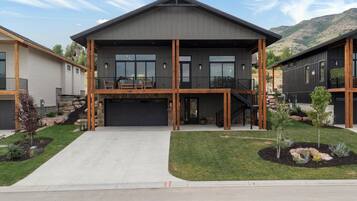 Une maison moderne à deux étages, dotée d’un garage, d’un balcon et d’une pelouse bien entretenue.