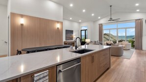 Una cocina moderna con una isla grande, paneles de madera y vistas al exterior.