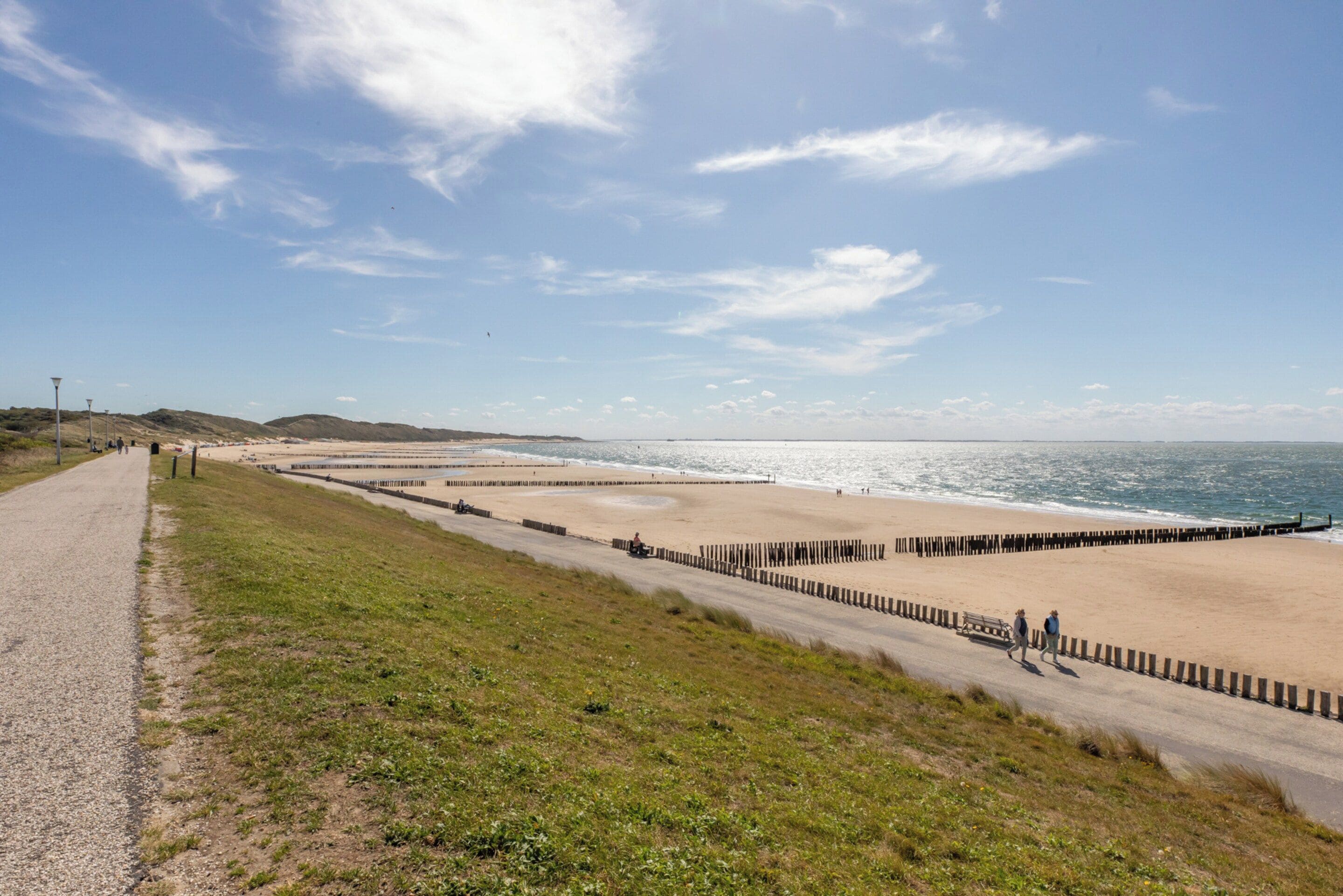 A coastal road with a beach on one side and a grassy area on the other.