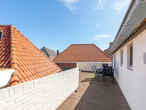Een terras op het dak met een bakstenen muur, een houten terras en een tafel met stoelen.