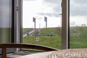 A view through a window with a grassy hill, a no parking sign, and a bench.