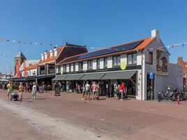 Calle peatonal con tiendas y un edificio con un letrero que dice 'Café'.
