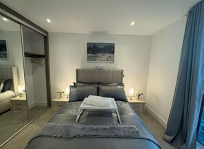 Relax in a serene space with a large bed, bedside tables, and a mirror.