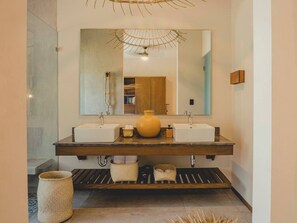 Een moderne badkamer met twee wastafels, een grote spiegel en een houten opbergmeubel.