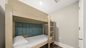 Ein Stockbett mit Holzrahmen und einem senffarbenen, gepolsterten Kopfteil.