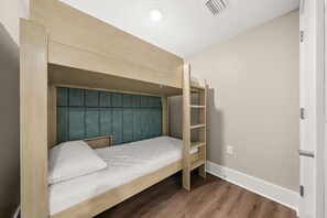 A bunk bed with a wooden frame and a teal upholstered headboard.