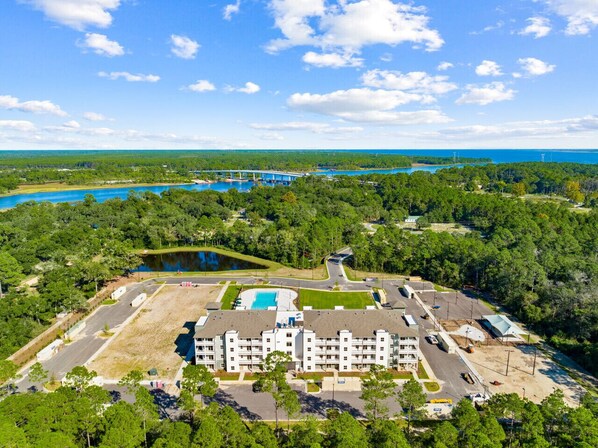 A large hotel with multiple floors, a swimming pool, and a parking lot. - Brand-New Condo w/ Zero-Entry Pool, Pickleball & More! (Panama City)
