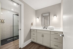 A modern bathroom with a white vanity, a large mirror, and a glass shower enclosure. - Brand-New Condo w/ Zero-Entry Pool, Pickleball & More! (Panama City)