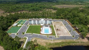 Ein Luftbild eines Hotels mit Schwimmbad, Tennisplätzen und Parkplatz.