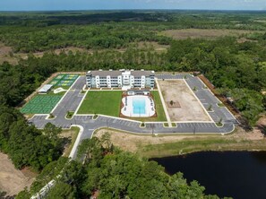 Vista aérea de un hotel con piscina, canchas de tenis y estacionamiento.