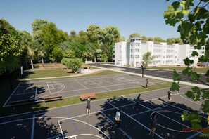 A basketball court surrounded by trees and a building with multiple windows. - Brand-New Condo w/ Zero-Entry Pool, Pickleball & More! (Panama City)