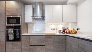 Eine moderne Küche mit integrierten Geräten, Holzschränken und einer Edelstahl-Dunstabzugshaube.