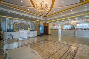 Eine Hotelhalle mit einer Rezeption, einer Kristallleuchtre und einem Marmorboden.