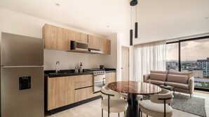 Une cuisine moderne dotée d’un îlot central, d’appareils électroménagers en acier inoxydable et d’un coin repas avec une table ronde et des chaises.