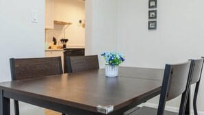 Una mesa de comedor con sillas, un florero y una cocina al fondo.