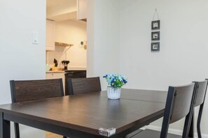 Un tavolo da pranzo con sedie, un vaso di fiori e una cucina sullo sfondo.