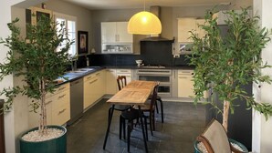 A modern kitchen with a central island, pendant lighting, and potted olive trees. - Charming house in Provence, quiet and pleasant (Aubignan)