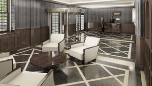 Una hall d'hotel con reception, area salotto e ascensore in vetro.