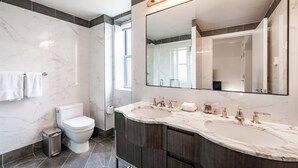 Un bagno moderno con un water, un bidet e due lavabi con uno specchio grande sopra.