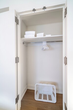 A walk-in closet with a hanging rod, shelves, and a storage basket. - Central Park Living | UWS, W/D & Rooftop (New York)