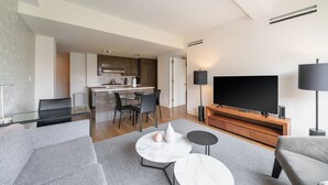 Un soggiorno moderno con una TV a schermo piatto, un divano, un tavolino e un'area pranzo con sedie.