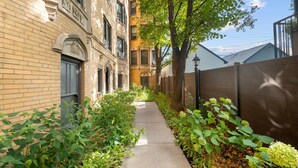 A narrow pathway flanked by brick buildings with large windows and a tree-lined path. - Guest Favorite Newly Renovated 1BR Near Lakeview (Chicago)