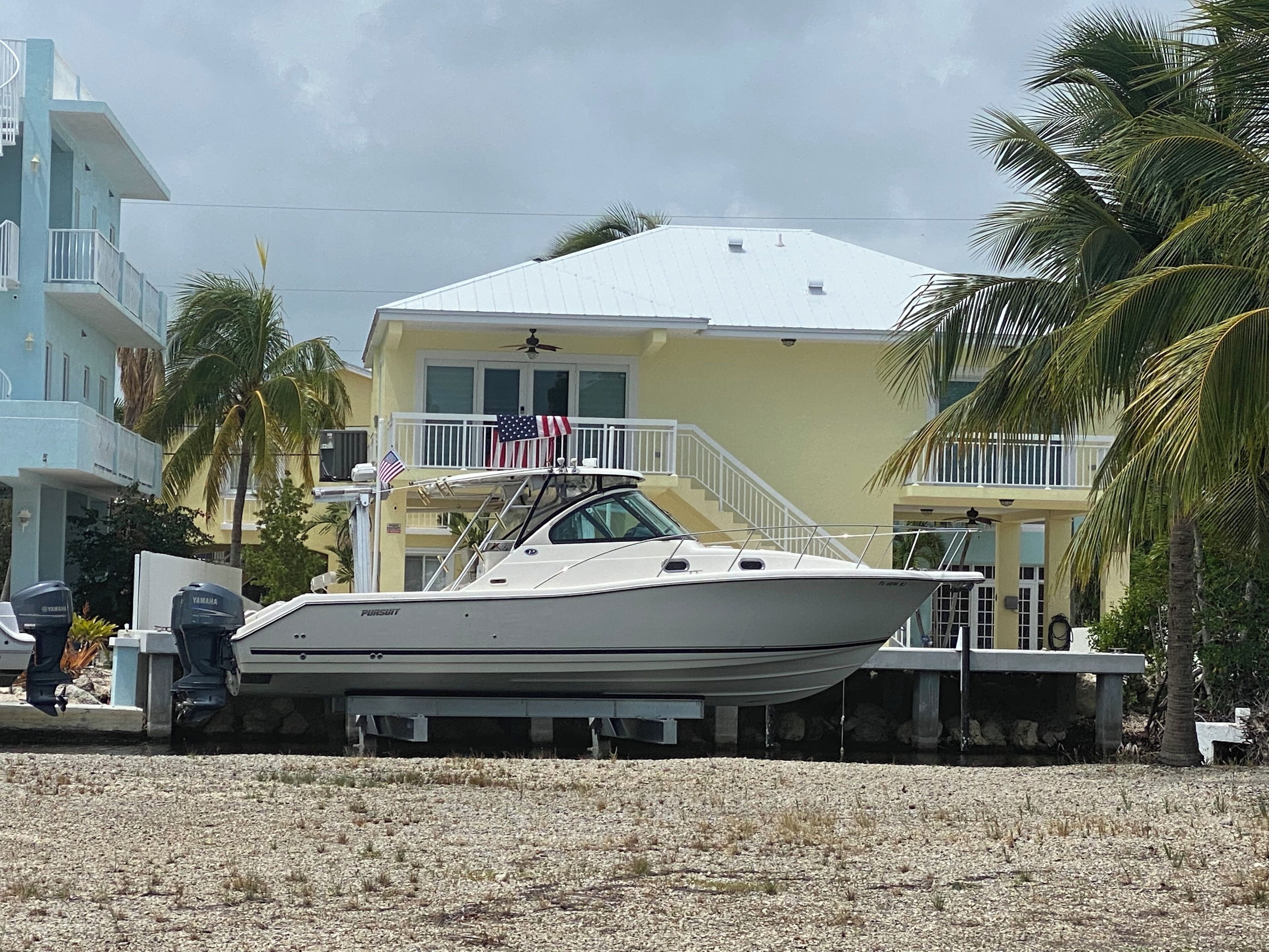 A boat docked in a marina with a building featuring balconies and a flag.