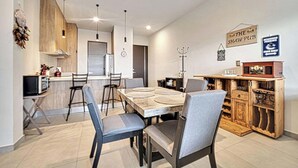 A modern kitchen with a dining area, a clock, and a sign for 'The Shaw Pub'. - OCEANVIEW 2 BR condo with AC, WiFi in enchanting Diamante area Cabo San Lucas! (Cabo San Lucas)