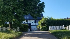 A gravel driveway leading to a traditional half-timbered house with a white picket fence. - Vacation apartment Sonnenhaus Oppenhausen directly on the "Ehrbachklamm" dream loop (Boppard)
