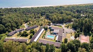 Vista aérea de um resort com vários edifícios, uma piscina e uma praia ao fundo.