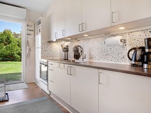 Una cocina moderna con armarios blancos, encimera de granito y cafetera.