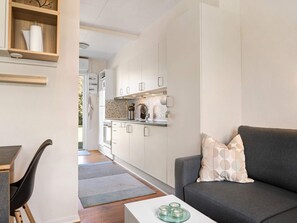 Un espacio habitable compacto con kitchenette, un sofá y una mesa de centro.