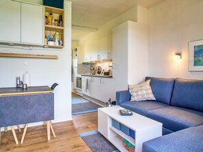 A modern living room with a sofa, a coffee table, and a kitchen in the background. - 4 Person Holiday Home in Nexo (Nexø)