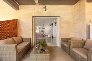 A living area with wicker furniture, a coffee table with decorative items, and a view into the adjacent room.