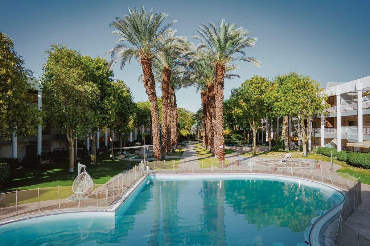 Una piscina rodeada de palmeras y un edificio de varios pisos.