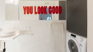 A modern bathroom with a sink, mirror, and a washing machine.