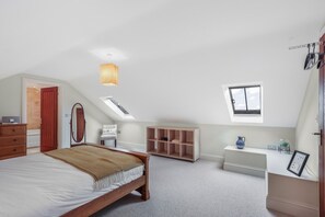 Een slaapkamer met een bed, een dressoir, een stoel, een bureau, een raam en ingebouwde kasten.