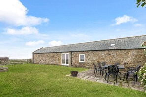 A stone building with a door and windows, a grassy yard, and outdoor furniture. - The Coach House - North East Escapes (Wandylaw)