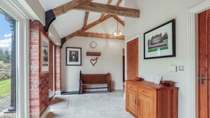 A hallway with exposed wooden beams, a bench, a wooden cabinet, and a framed picture on the wall.