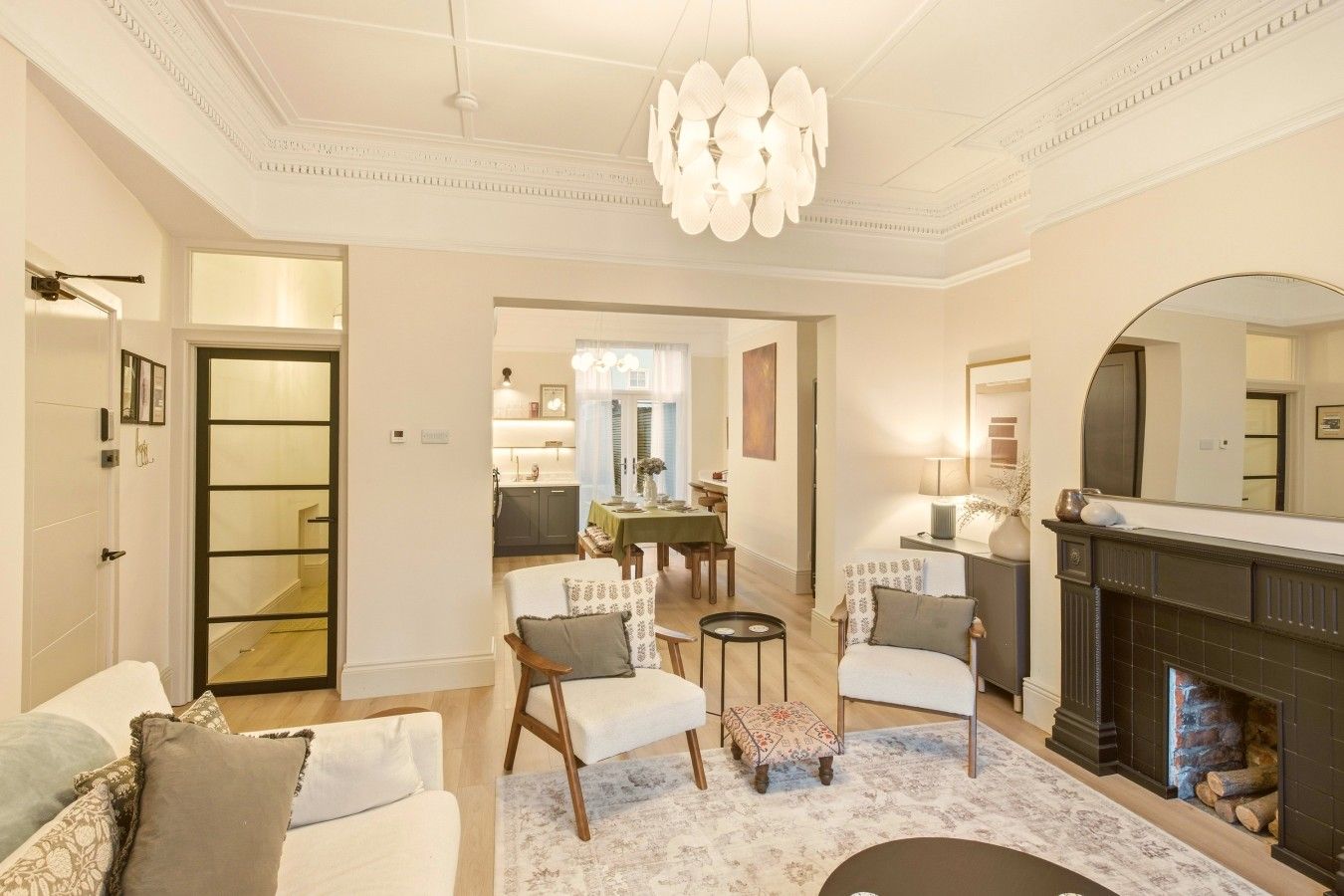 A spacious living room with a fireplace, a dining area with a table and chairs, and a kitchen in the background.