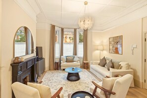A spacious living room with a fireplace, a sofa set, a coffee table, and a chandelier.