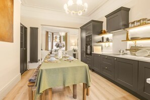 A modern kitchen with dark cabinetry, a dining table set for six, and a chandelier.