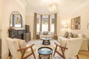 A living room with a fireplace, sofas, a coffee table, and a television. - St George's Apartment - North East Escapes (Jesmond)