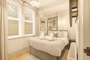 Bright king-size bedroom with large windows and built-in shelving