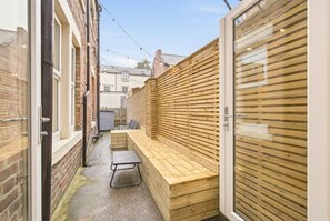 Private backyard with built-in wooden bench seating and privacy screening - St George's Apartment - North East Escapes (Jesmond)