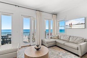 Relax in this ocean-view living room with a large sofa, coffee table, and balcony seating.