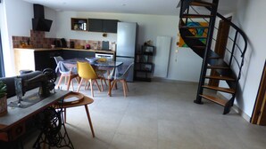 A modern kitchen with a dining area, a staircase, and a sewing machine. - Country house in Brière, 20 minutes from the beach. (Donges)