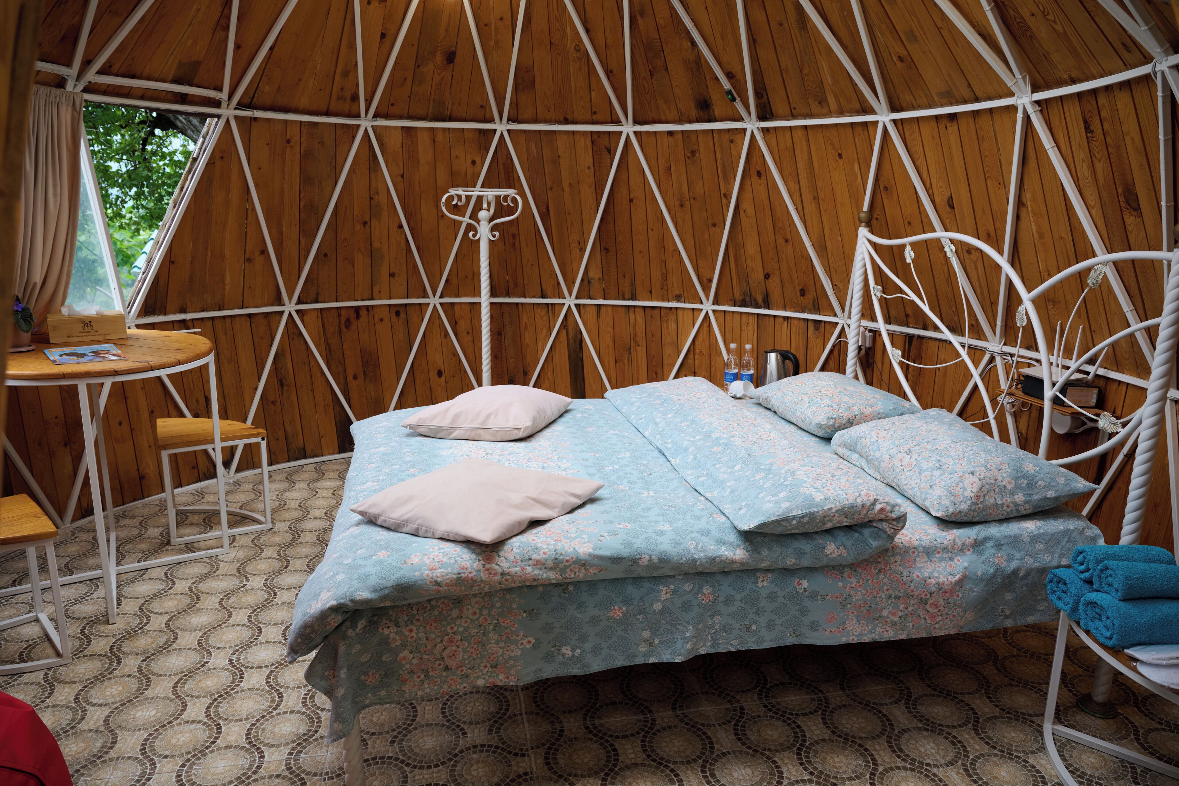 A cozy, circular wooden tent with a bed, a small table, and a chair.