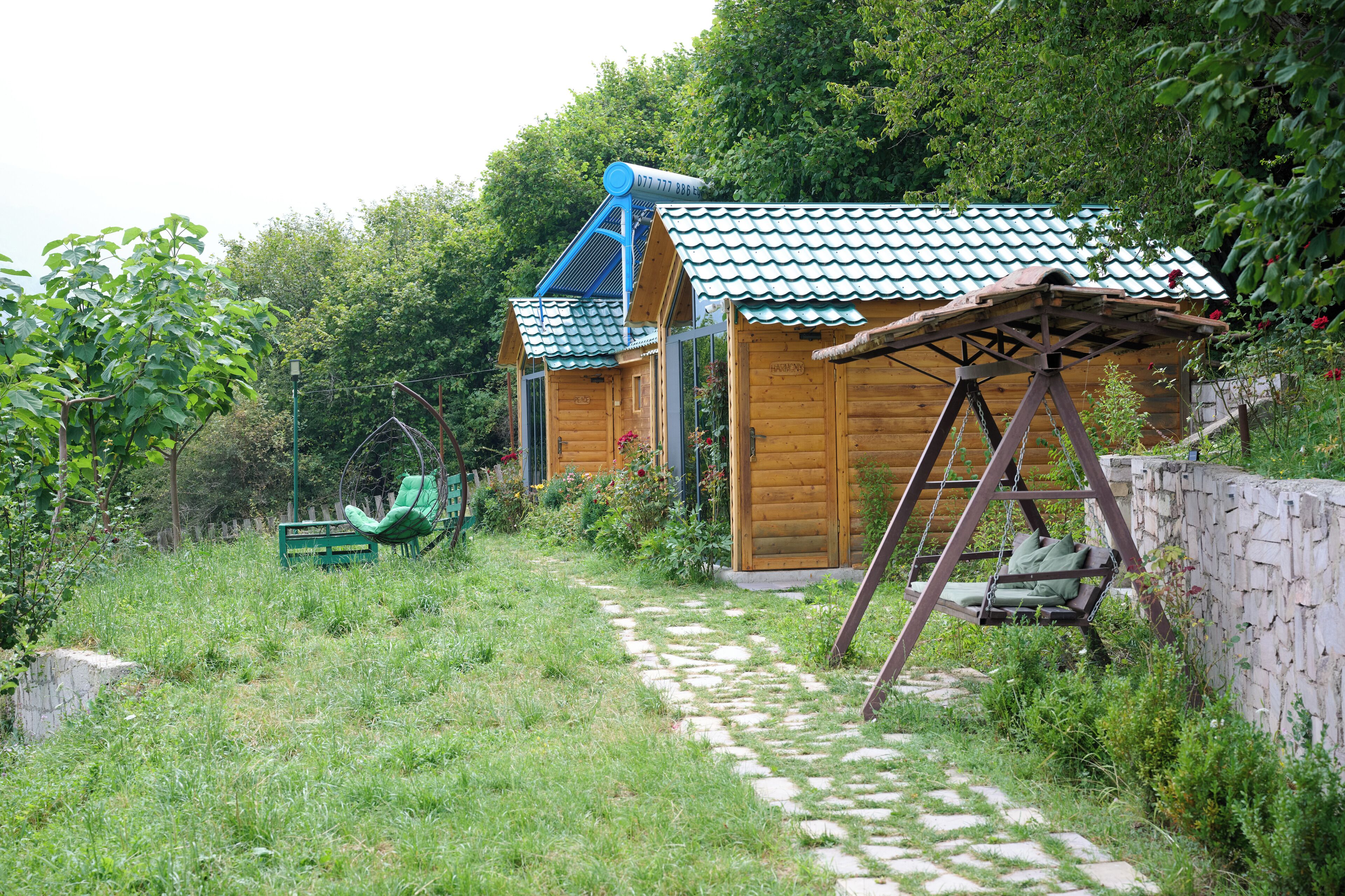 Uma cabana de madeira com telhado verde e um balanço em primeiro plano.