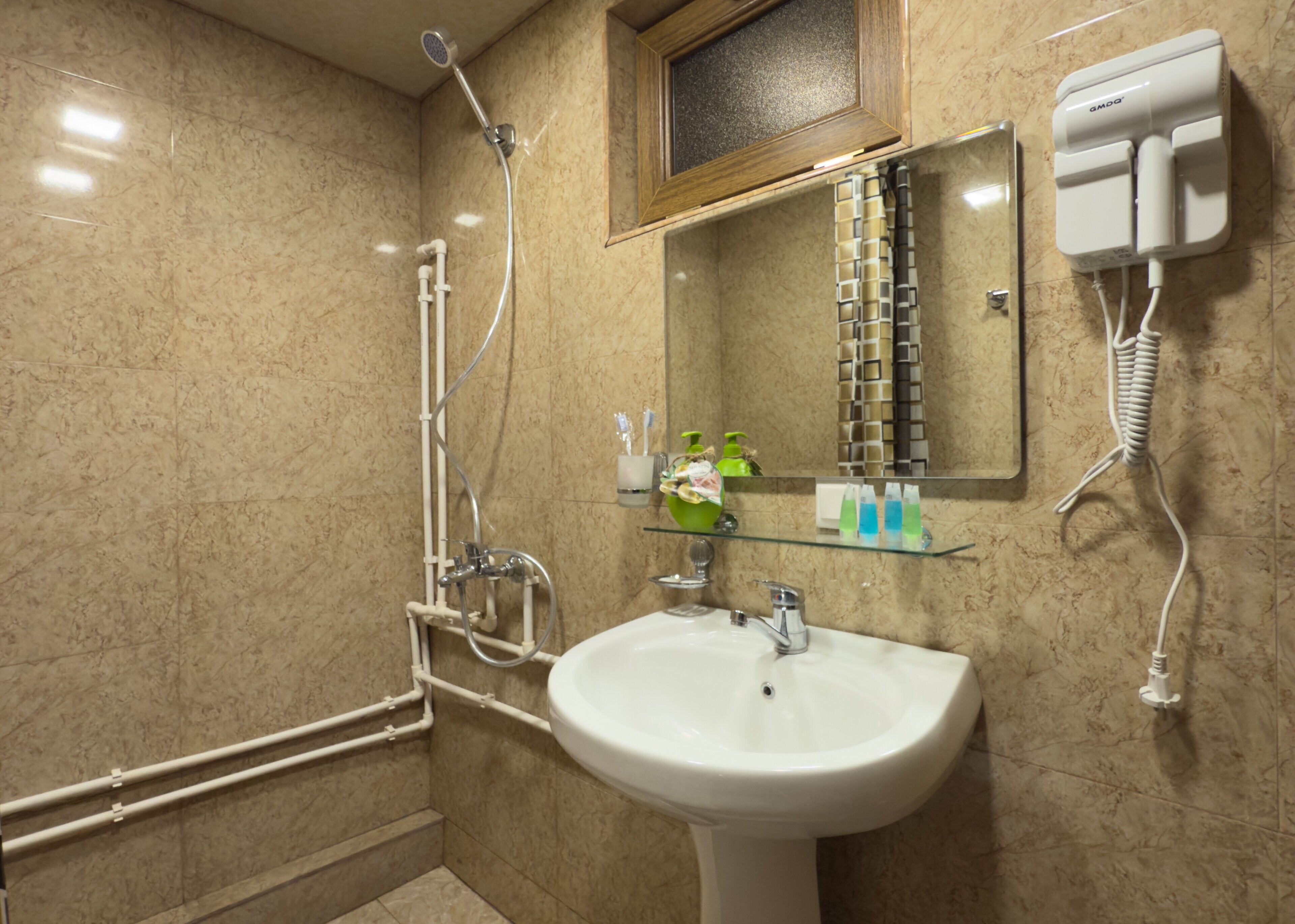 A bathroom with a shower, sink, and a mirror.